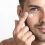 close-up-of-young-stubble-man-applying-cream-on-her-face (1) (1)